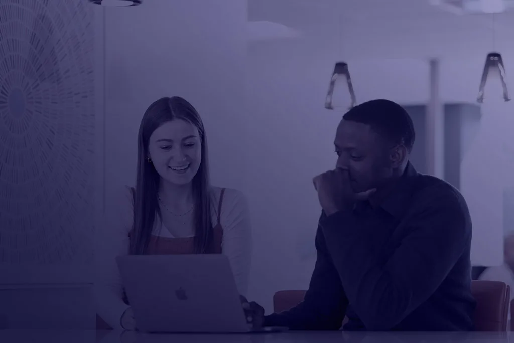 Two Avint colleagues talking at a laptop